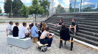 Gruppenfoto Menschen vor Hochschule sitzen auf Stühlen Carsten_Schelling_Entwurf 45_SoSe 2025