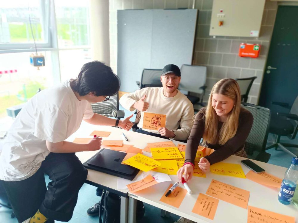 Eine Gruppe von Drei Menschen sitzen zusammen und machen Design Thinking